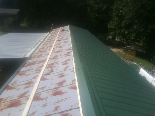 Old rusted panels beside newly installed green metal roofing — Wind Damage Roof Repair by Roofing Brothers in Hurleyville