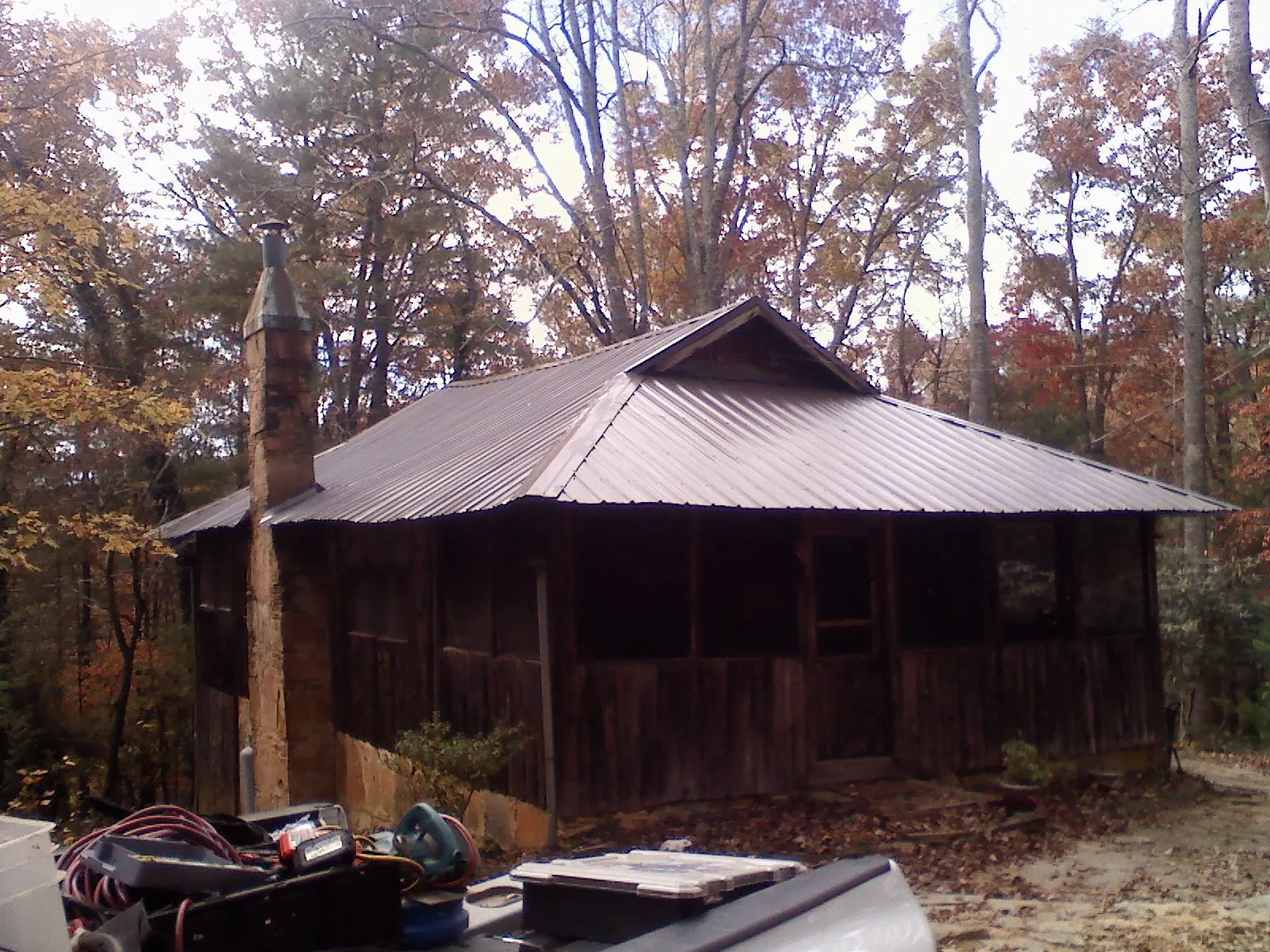 Brown metal hip roof on an old cabin with a stone chimney in Hurleyville