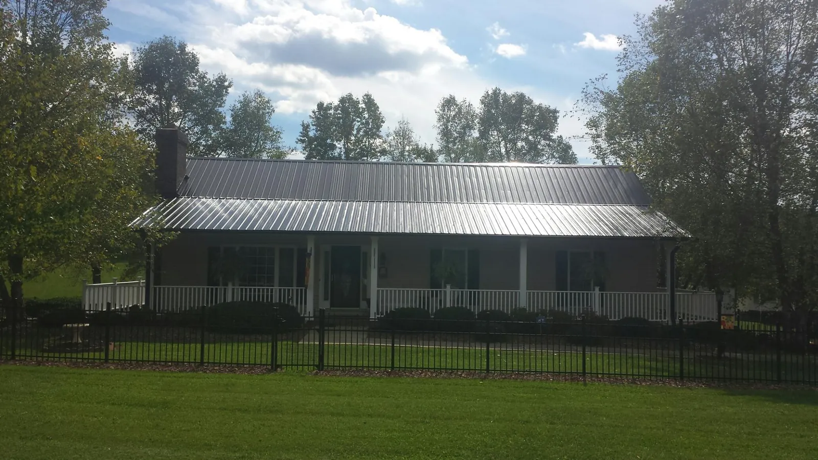 Gray metal roof on a brick ranch with a full width front porch — Gutter Guard Installation work by our crew in Hurleyville