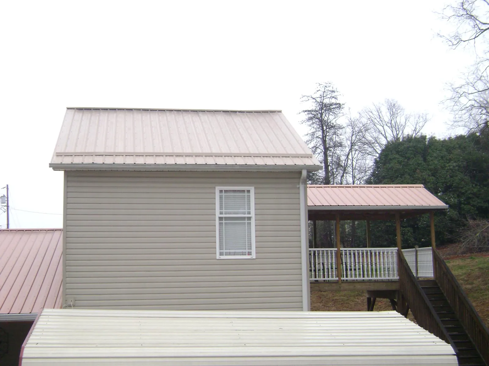Tan metal roofs on a two story addition and attached porch, from a Roof Replacement job in Hurleyville