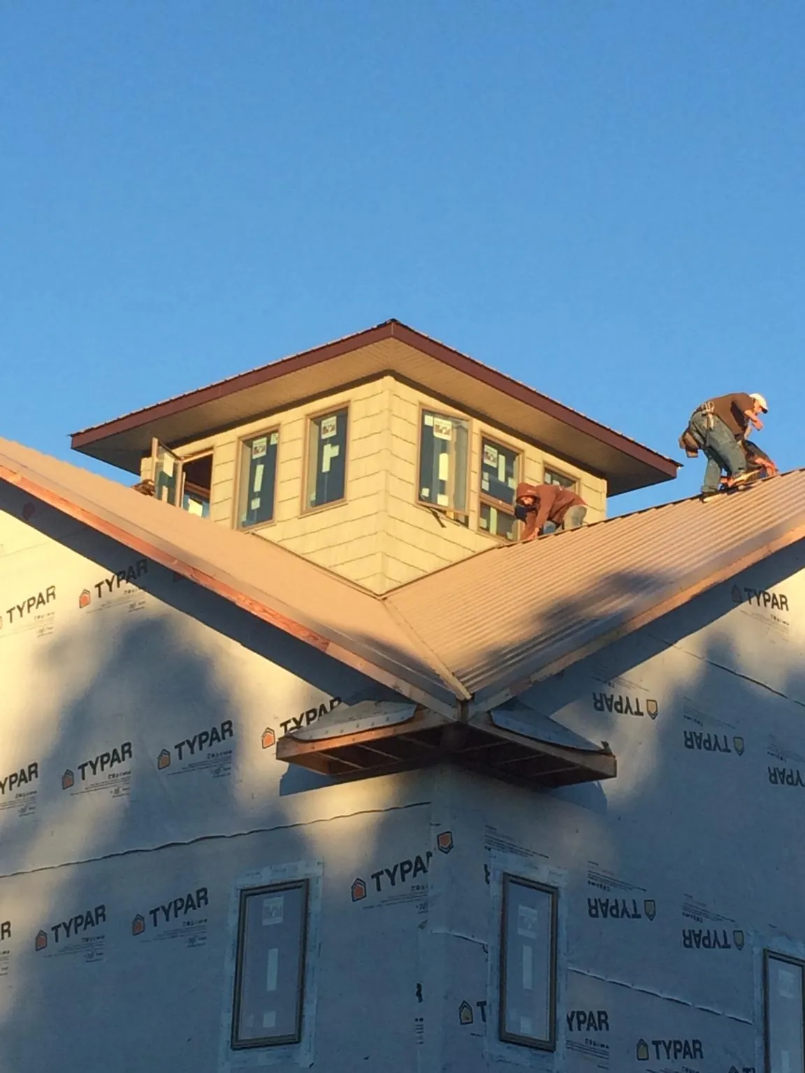 Roofers working around a rooftop cupola on a new metal roof at sunset — Roof Waterproofing in Hurleyville by Roofing Brothers